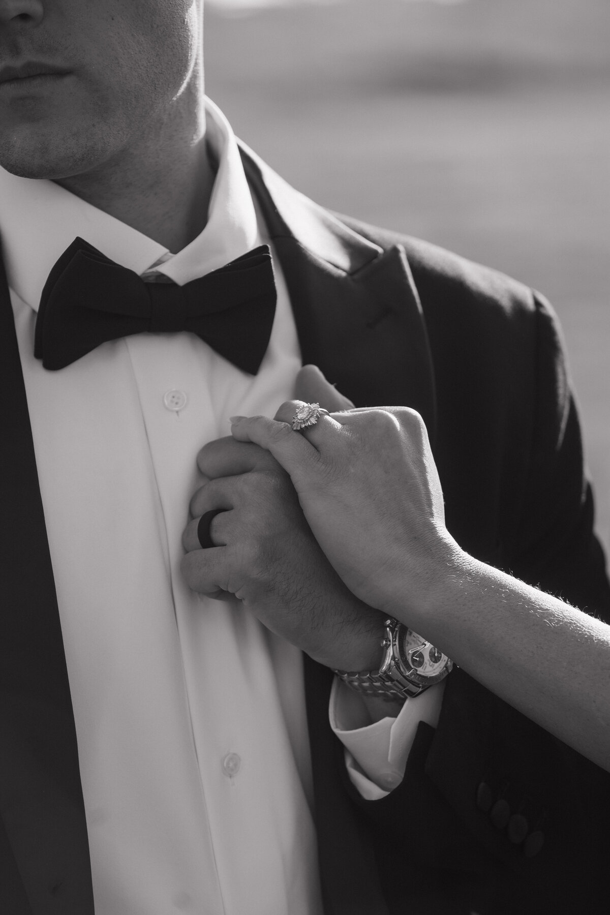 Black and white editorial photography of bride and groom's wedding rings and bowtie. 