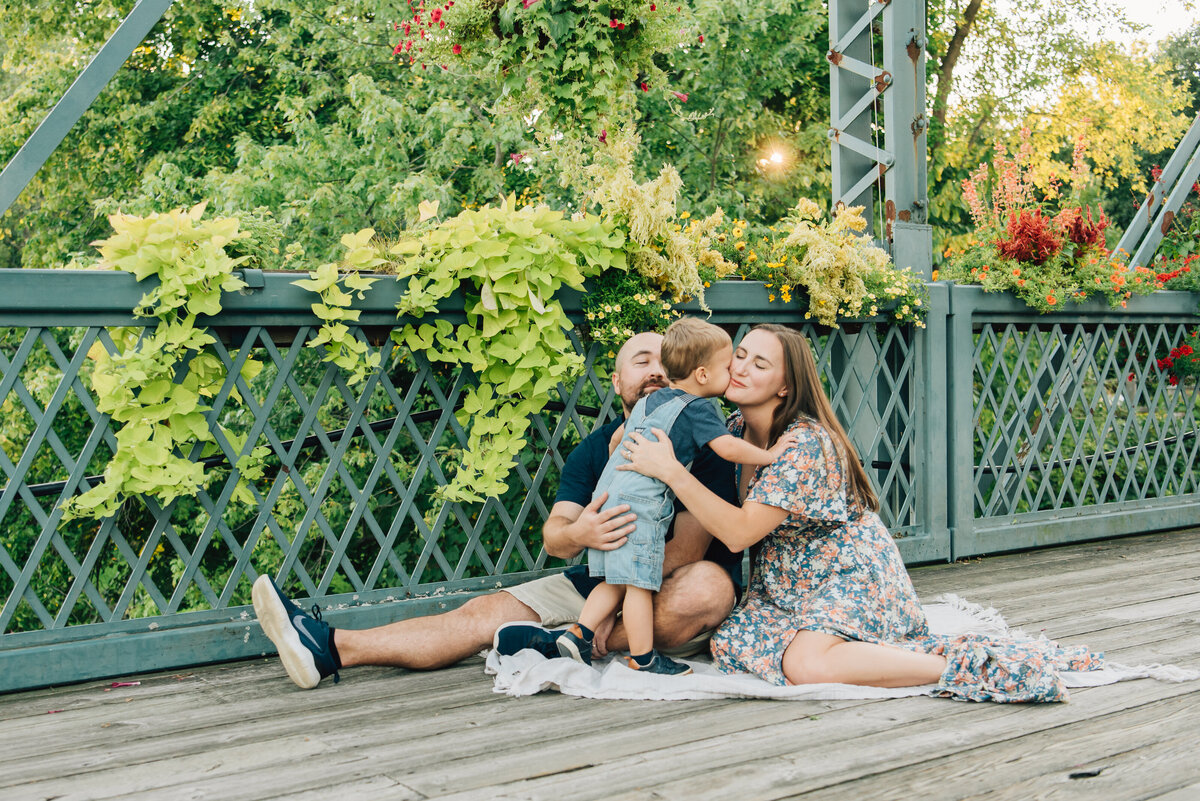 Family of three hugging on bridge