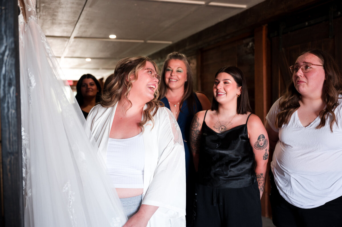 bride and bridesmaids admiring wedding dress