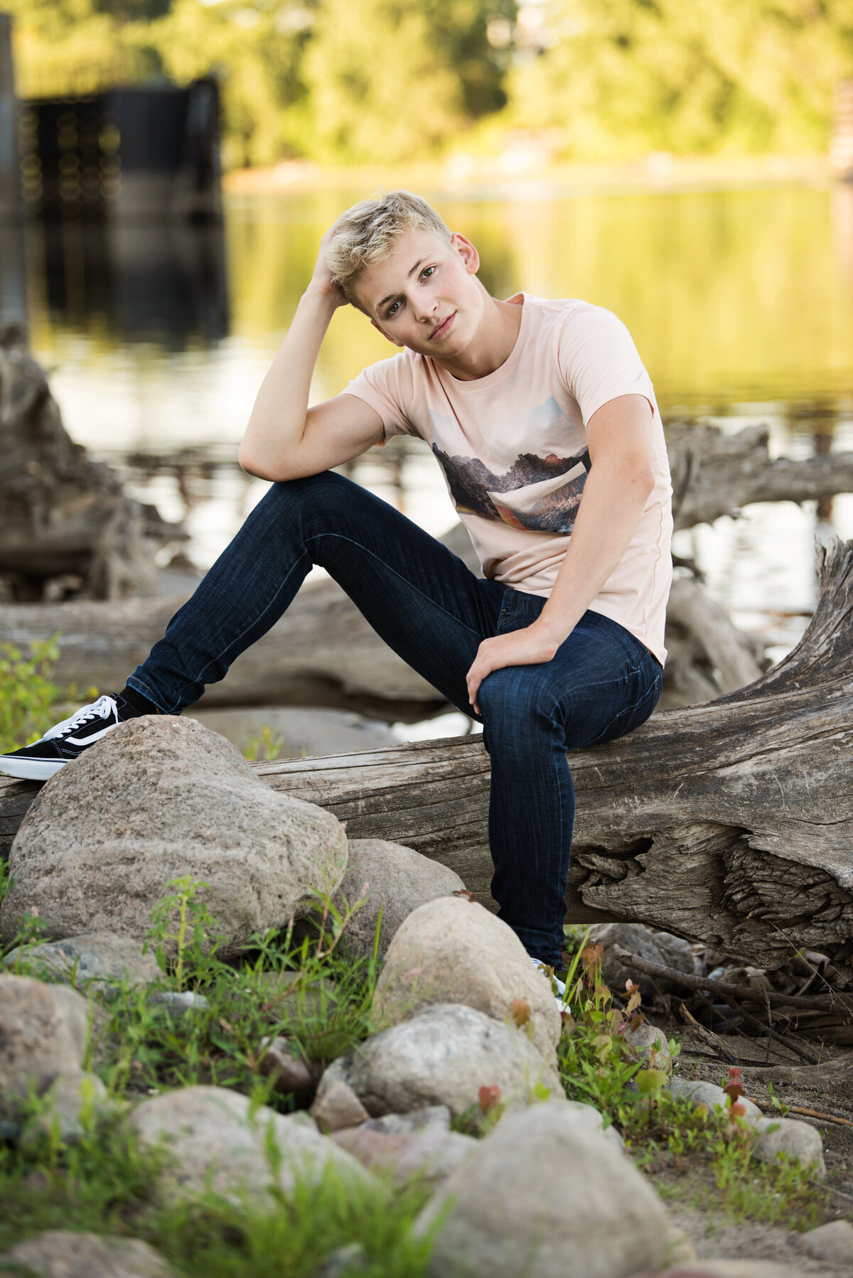 grad photo of boy on driftwood with jeans and t-shirt on driftwood