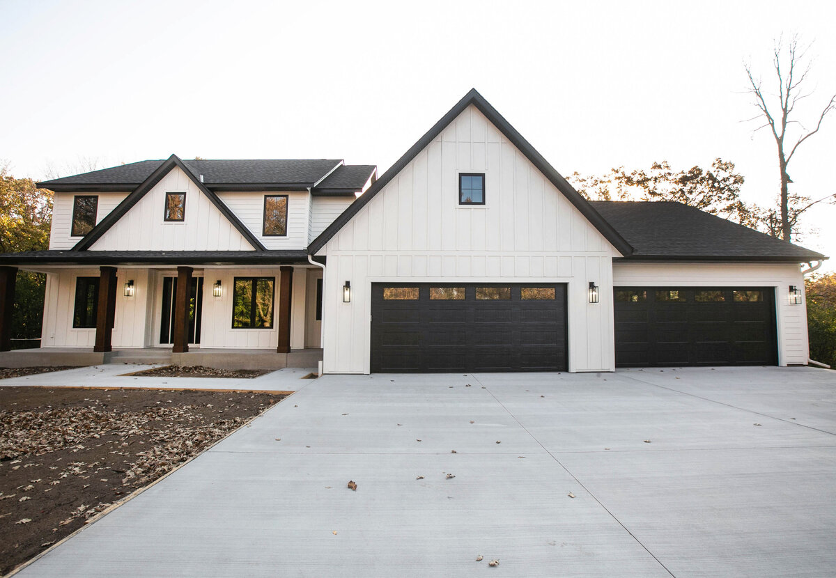 Exterior view of custom home in Big Lake Township, Minnesota with farmhouse details, cream siding, wood pillars and front porch built by Cornerstone Custom Builds
