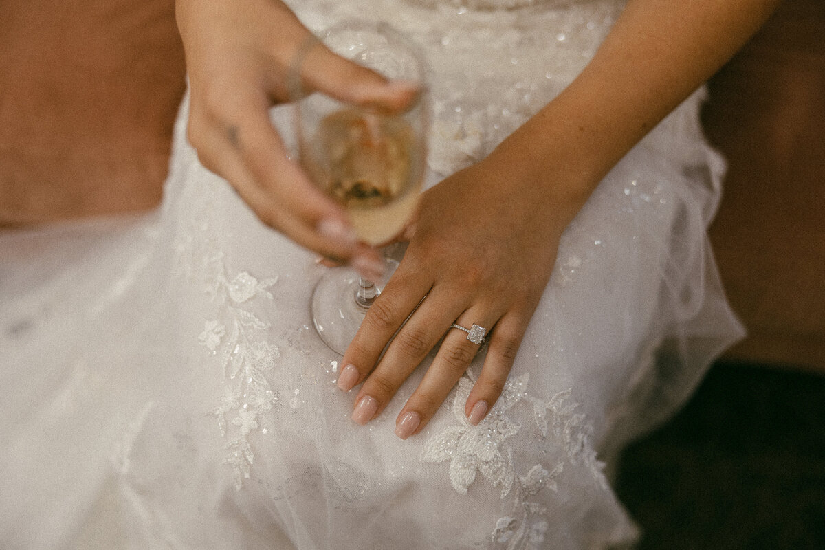 A hand resting on their leg with a champagne glass in the other hand.