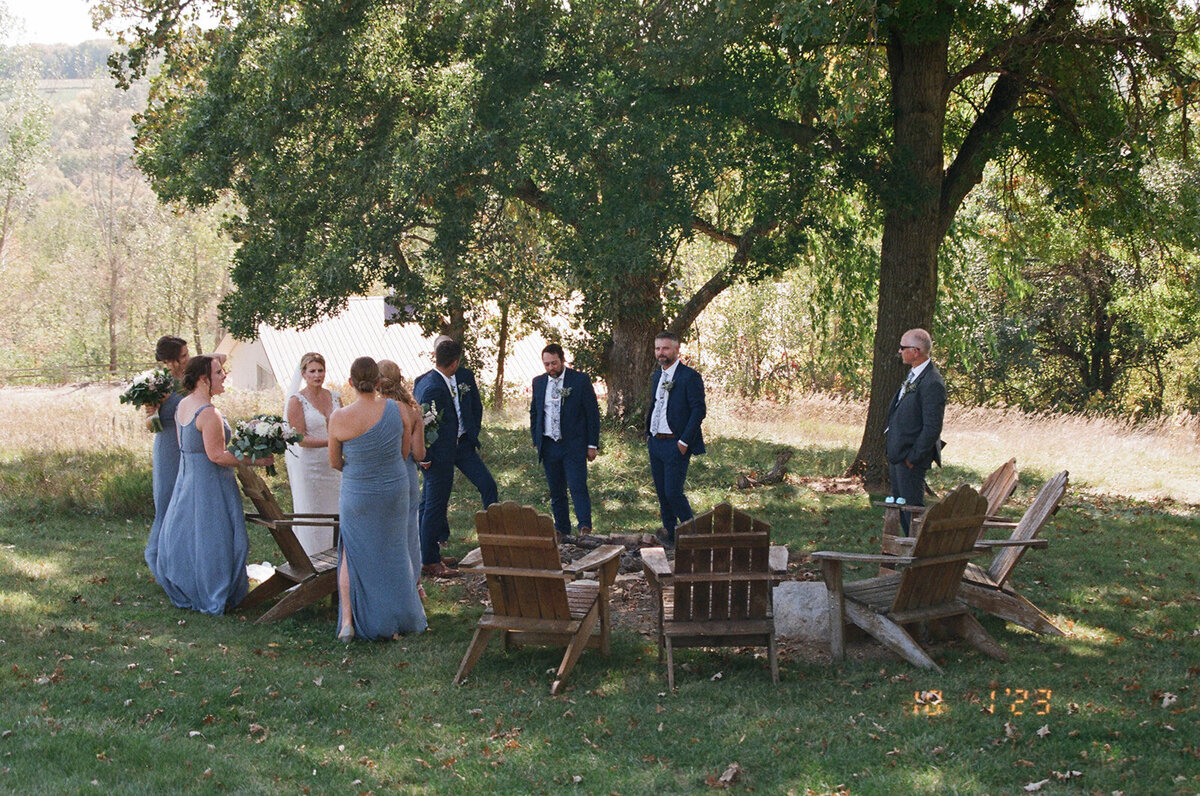 bridal party sitting and standing around lawn chairs at a Minnesota winery.