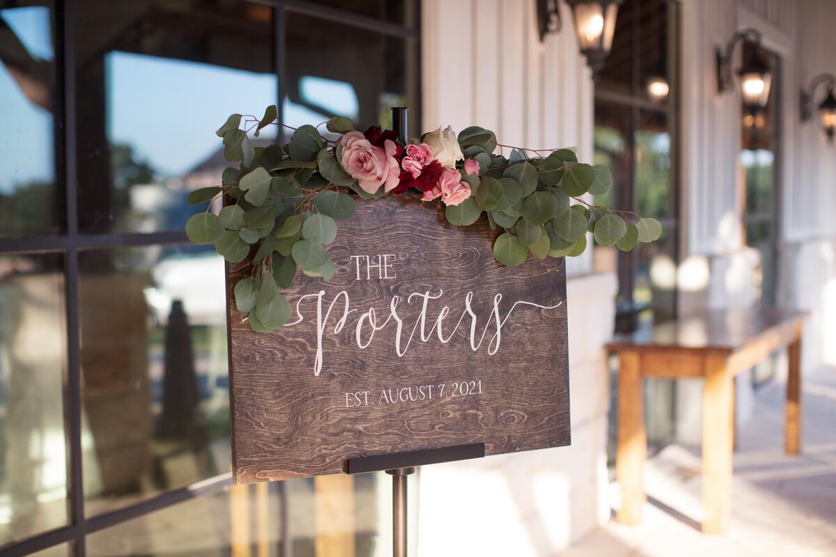 wood sign outside wedding venue with couple's last name and date by Firefly Photography
