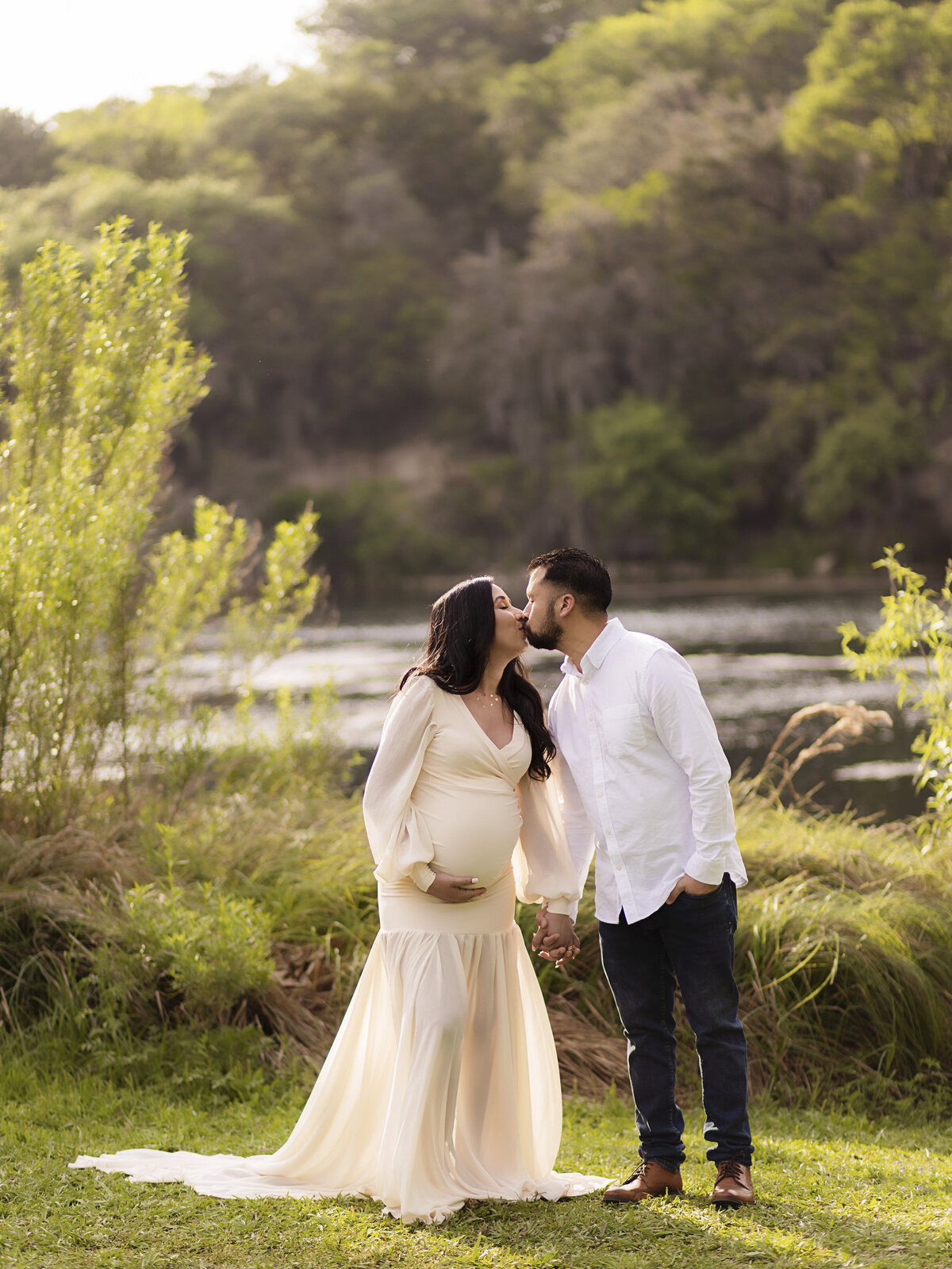 pregnant mother kissing husband outside while holding hands