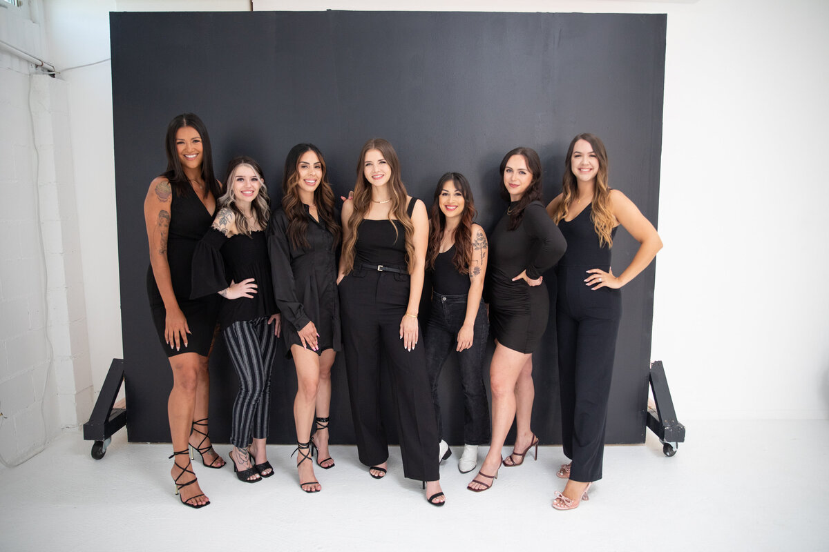An elegant group of women posing in front of a black background captured by an Austin wedding photographer.