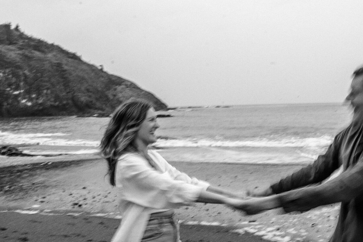 A blurry image in black and white of holding hands and spinning. 