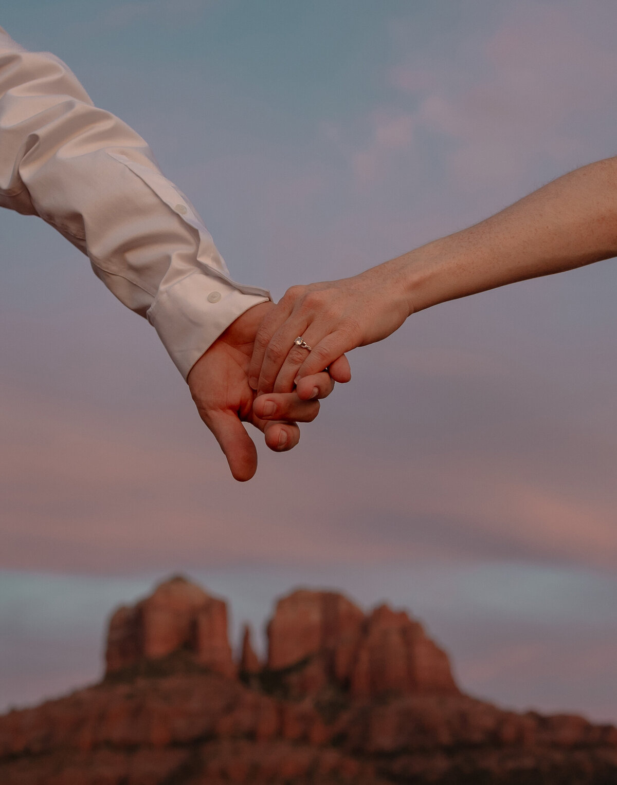 Couple standing against red rock backdrop during Sedona engagement session