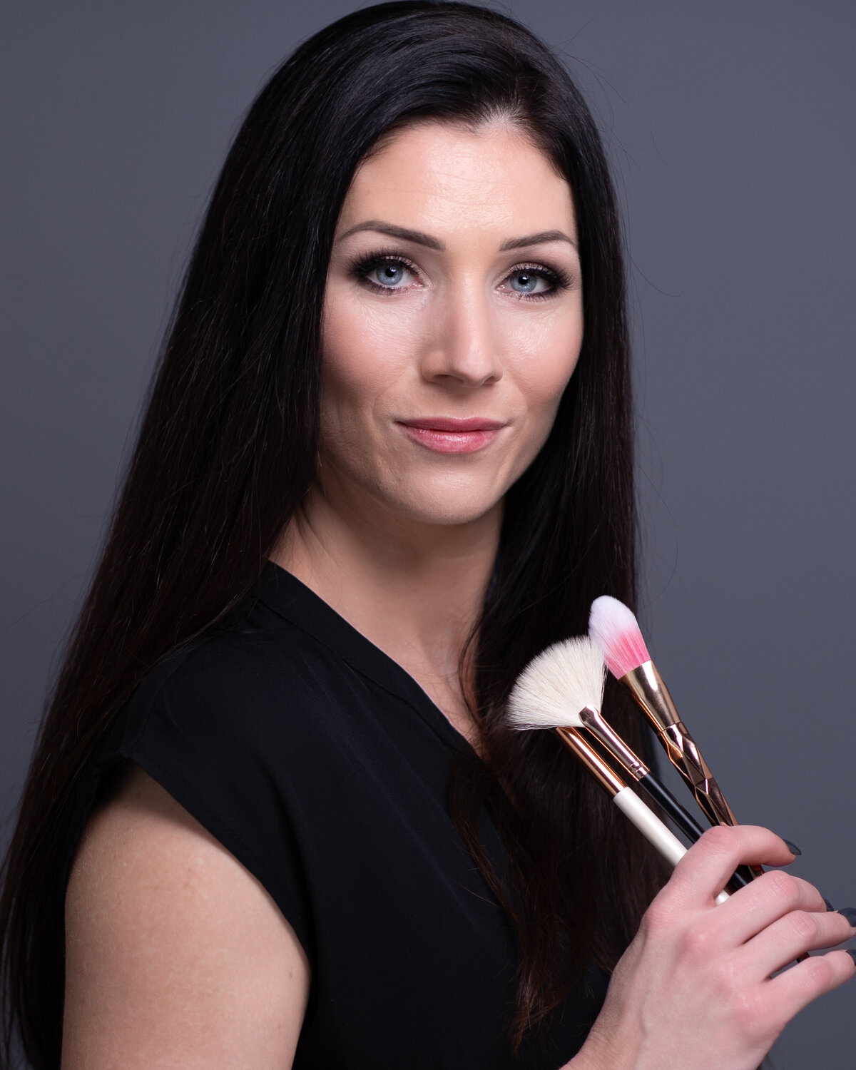 closeup branding image of makeup artist holding her brushes