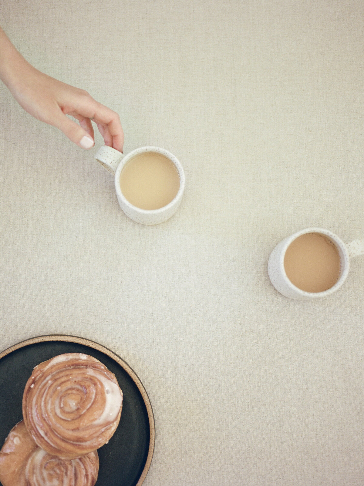 flat lay of coffee cups, hand reaching, cinnamon rolls, fika during designer branding film photos