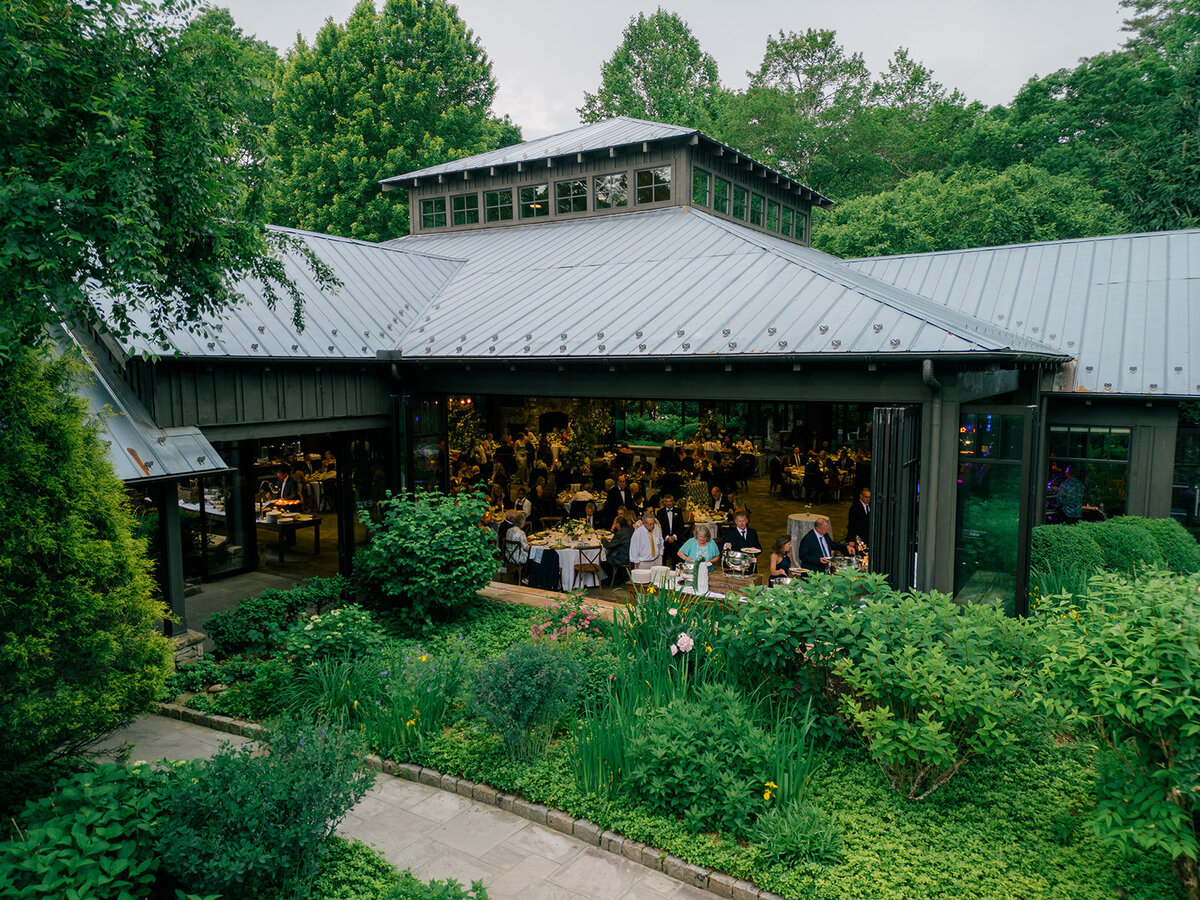  View of reception through open pavilion doors surrounded by lush landscaping at Old Edwards Inn in Highlands, North Carolina.