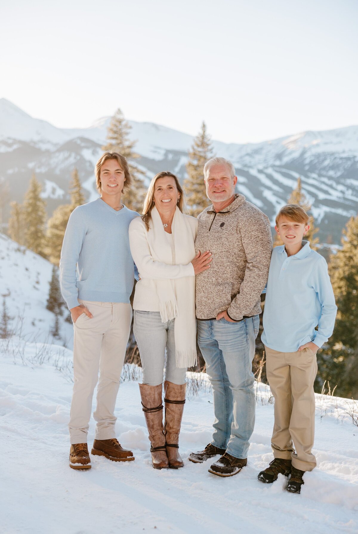 A family stands together smiling in blue and tan on a snowy mountain