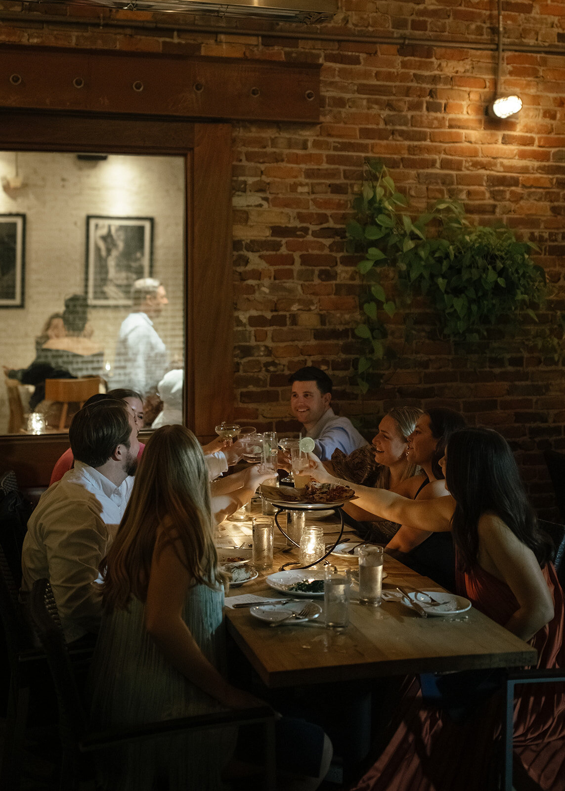 Group of friends and family clinking glasses in the center of table at rehearsal dinner