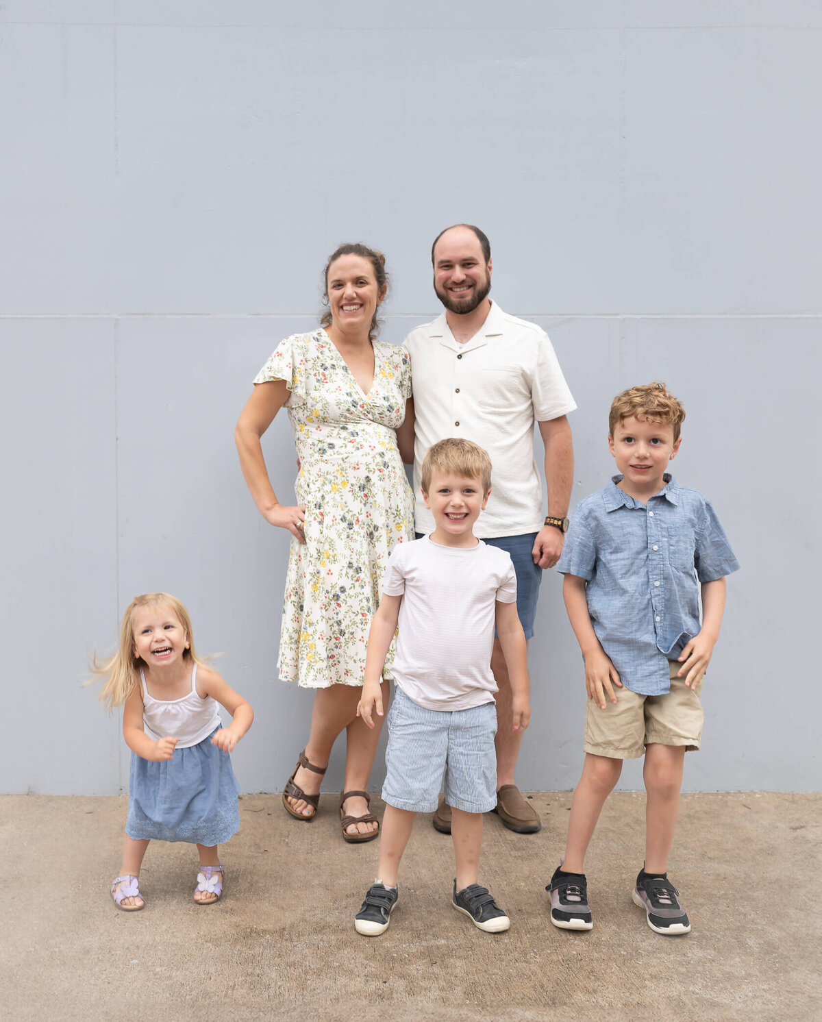 cutest family in front of a blue wall downtown