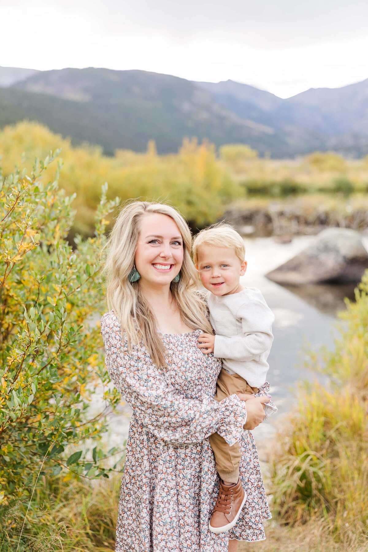 mom and son smile for photo with water behind them and fall colors in Estes Park, Colorado