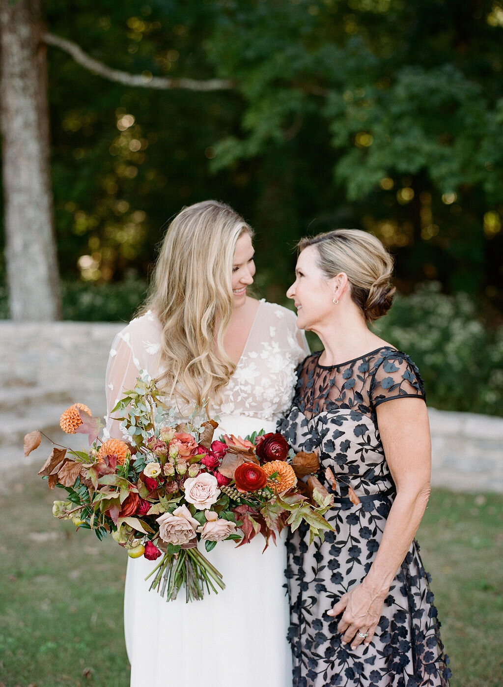 A whimsical bridal bouquet filled with burgundy, terra cotta, dusty rose and burnt orange florals. The bouquet features ranunculus, garden roses, dahlias, fruiting branches and autumn foliage. Designed by Rosemary and Finch in Nashville, TN.