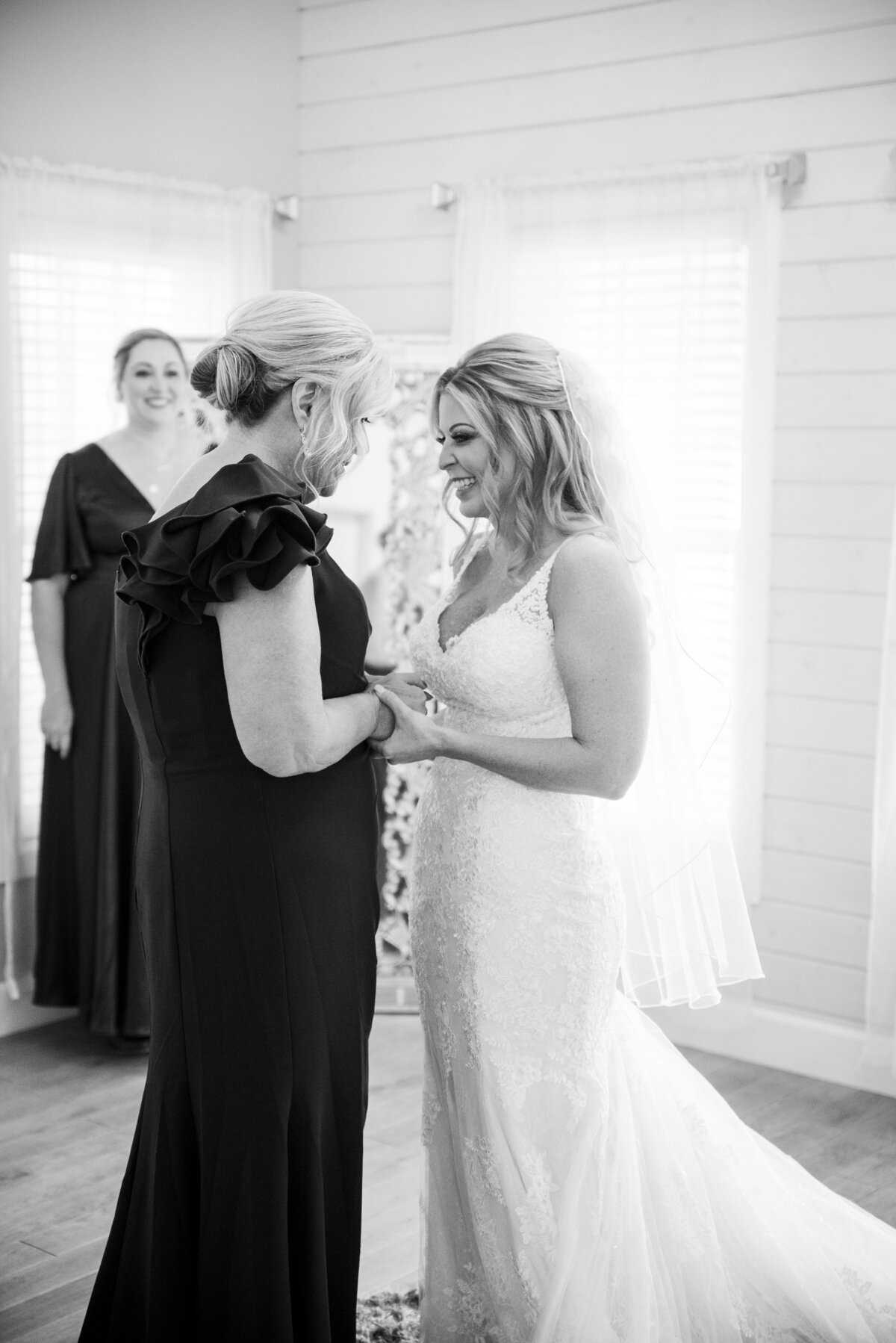 A bride and mom smile at each other and hold hands in a sentimental, candid moment captured by Denver wedding photographer, Casey Van Horn.