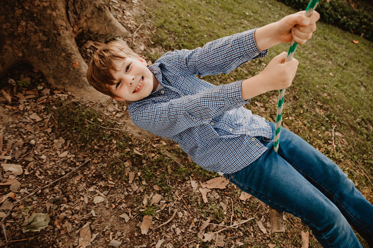 A child smiling and swinging on a rope swing