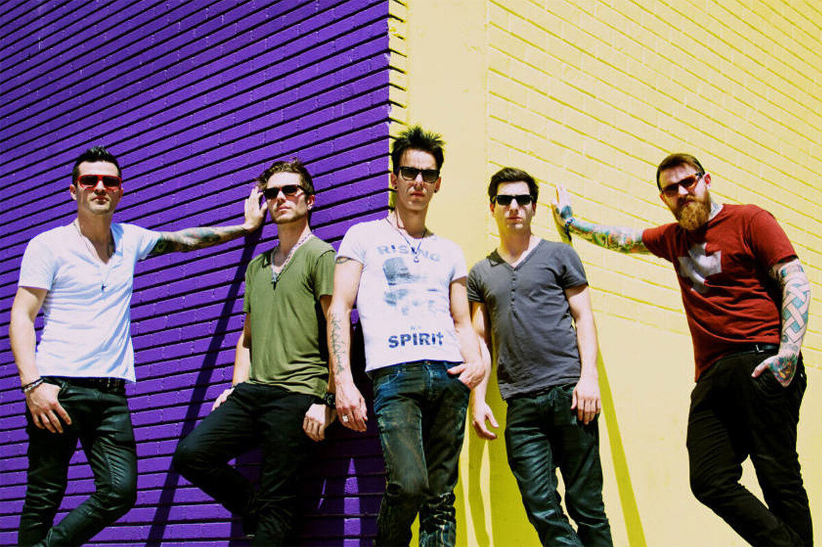 Musical group portrait five members standing against corner of building painted with purple and yellow walls The New Electric