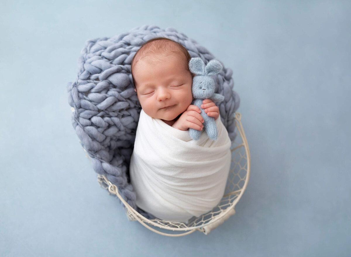 Smiling two-week-old newborn lying on a soft, neutral backdrop during a classic NYC baby photoshoot