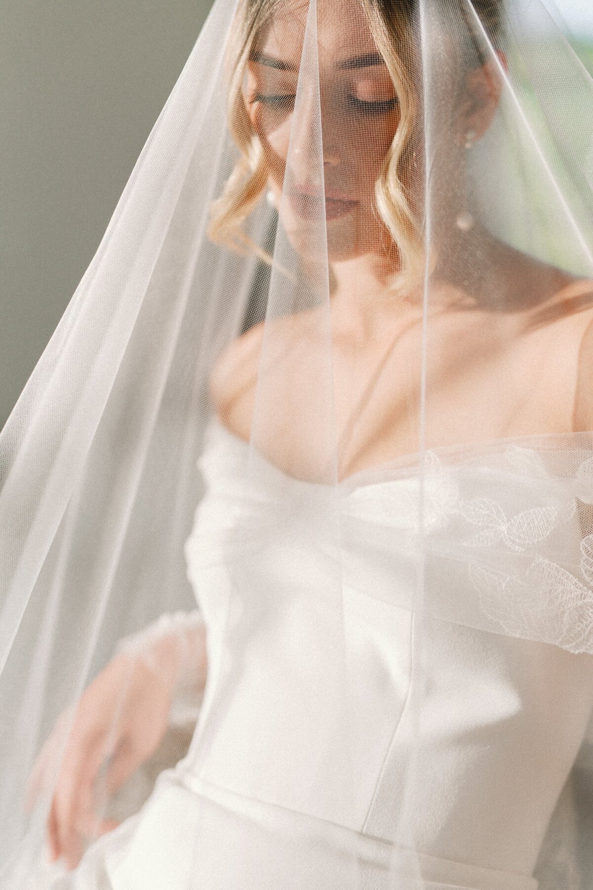 Bride relaxes in chair under her veil as the warm sun pours in by Lacey Graham Wedding photographer
