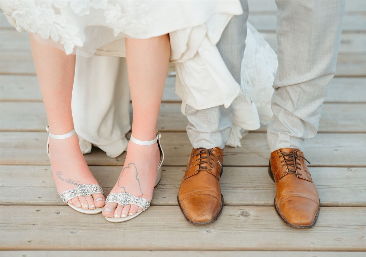 a couple's feet with their wedding shoes