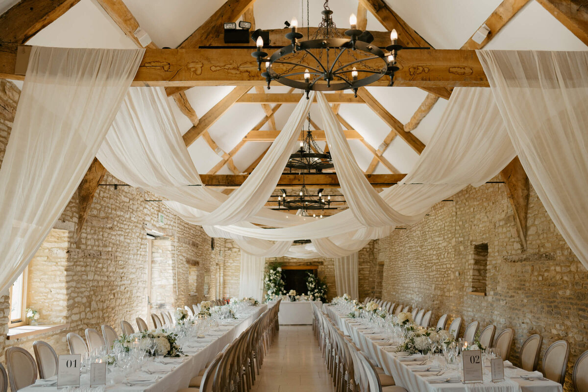 Barn reception space at Caswell House styled with soft drapery across the beams
