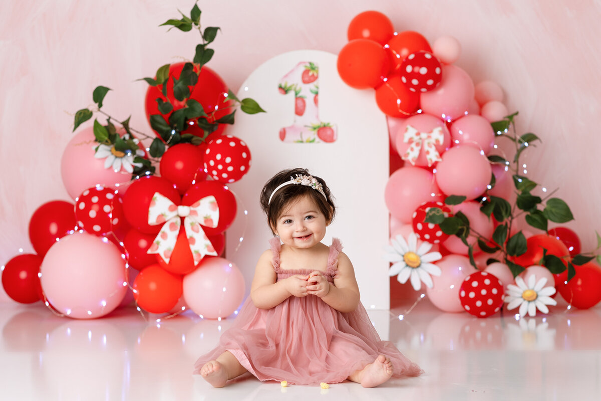 One year old Tampa baby enjoying a personalized luxury cake smash session with playful berry decorations