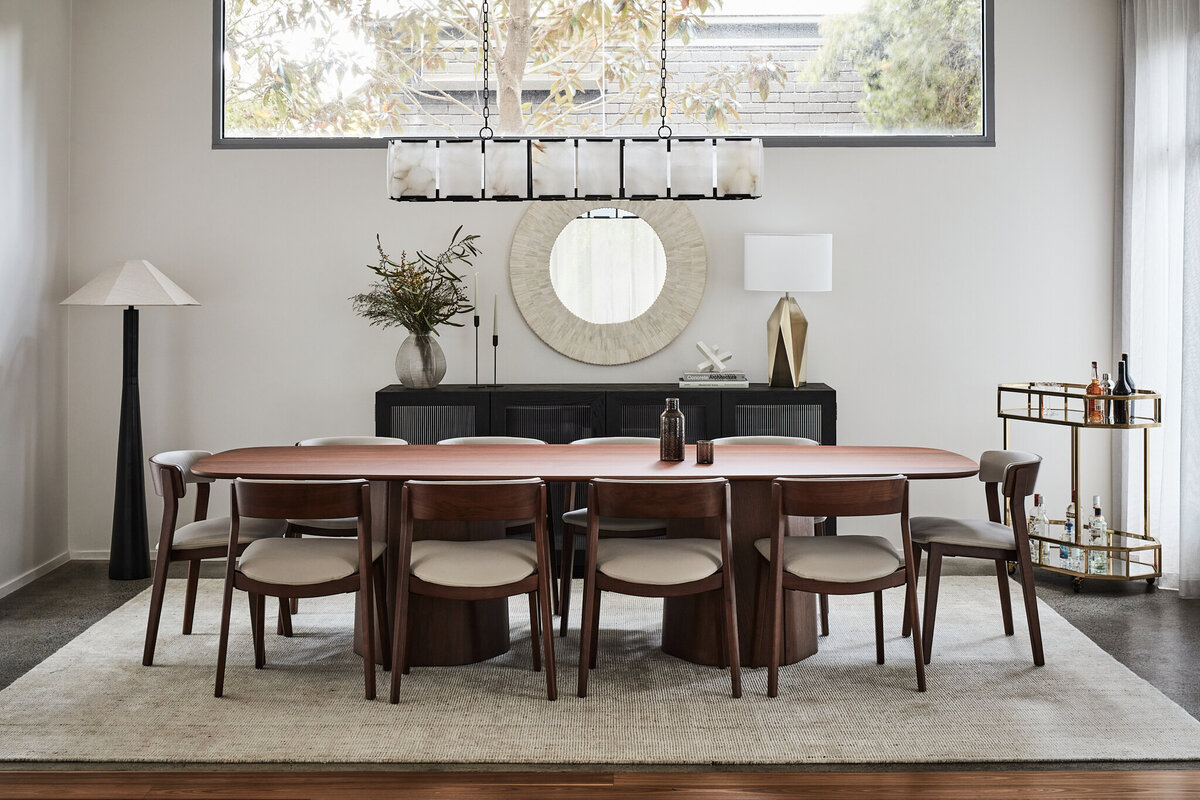 Refined dining space with timber dining table, sculptural chairs, pendant lighting, and a brass bar cart in a Brighton home designed by Lisa Hunter Interiors.