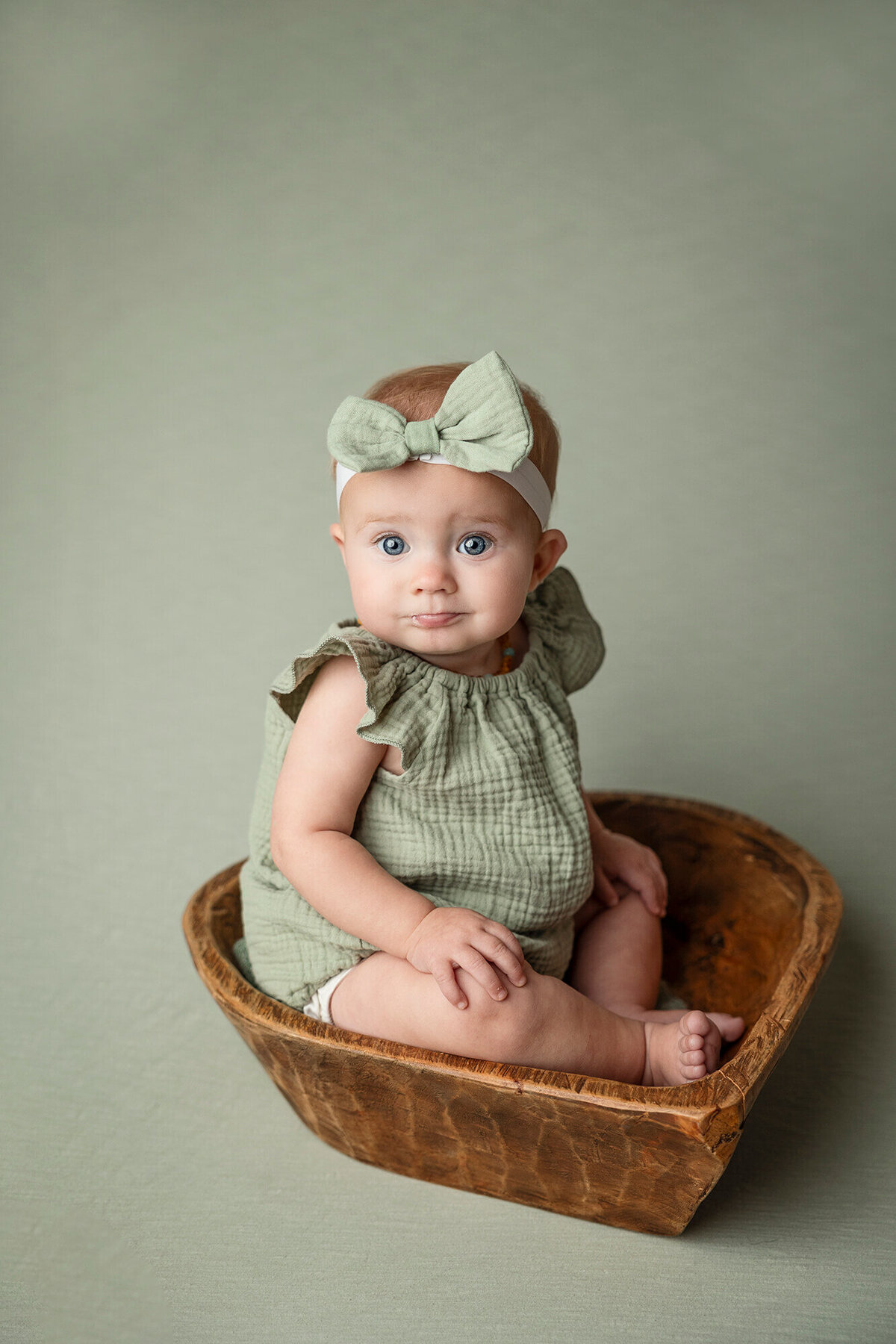Baby girl in green posed in a heart bowl in Southern MN.