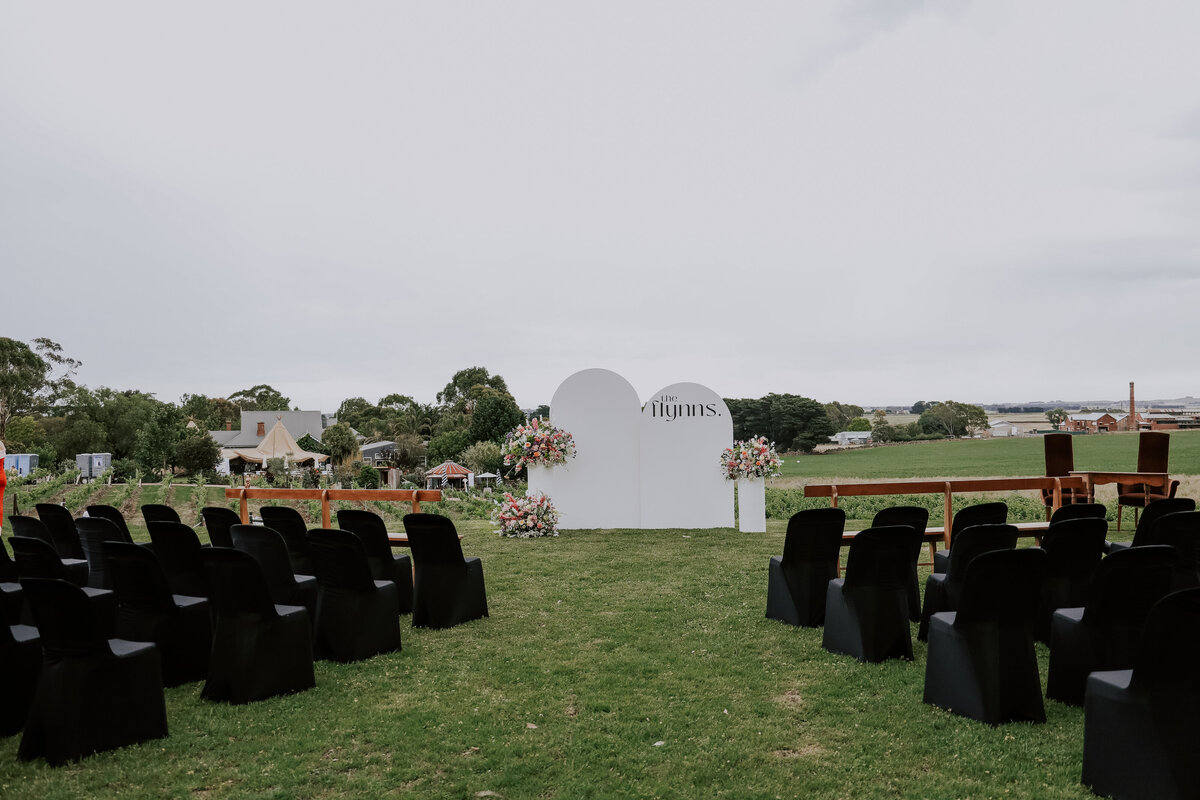 Personalised signage and styled flower arrangements and seating at a wedding ceremony