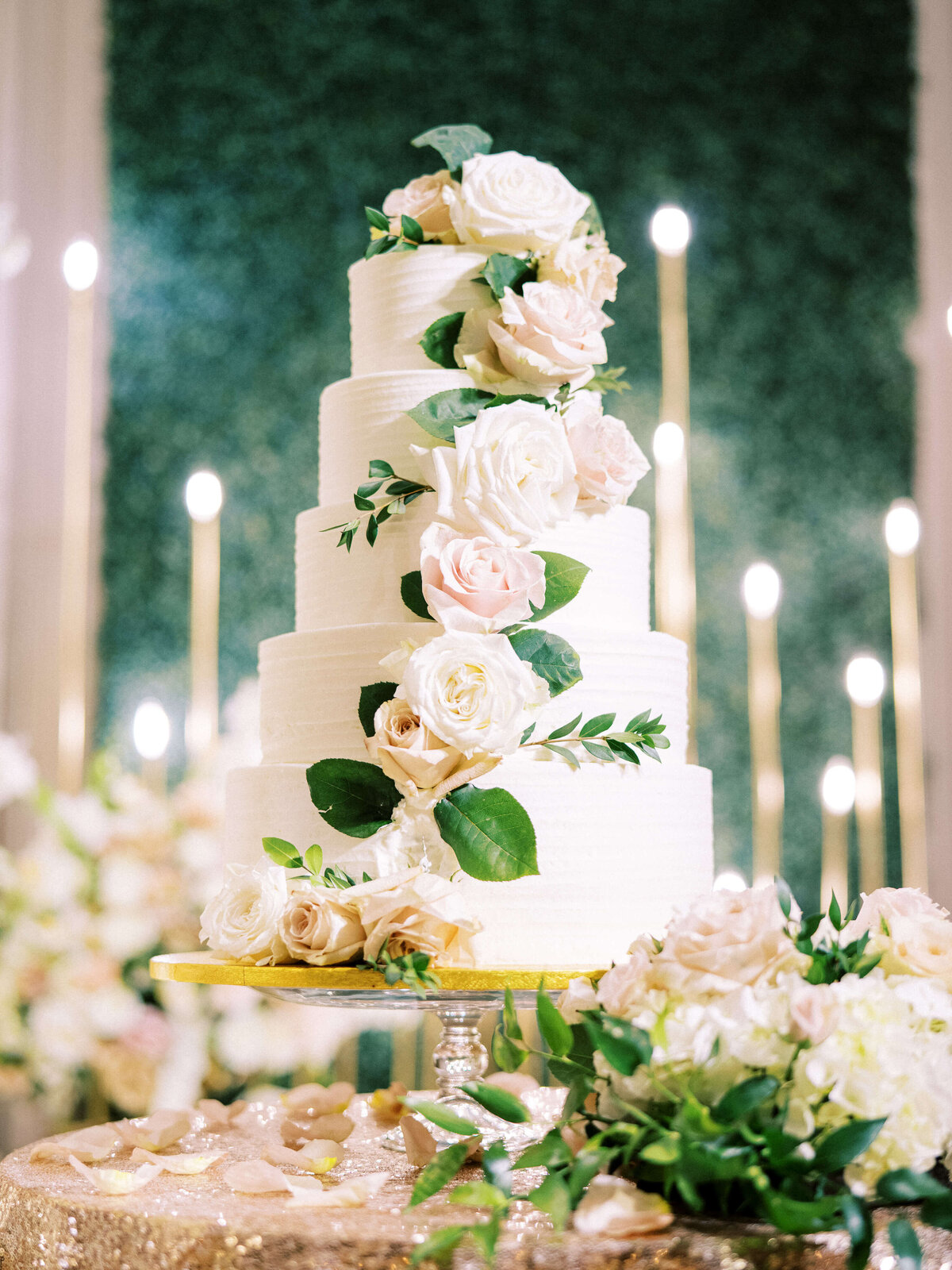 Romantic white wedding cake with roses and greenery and candles