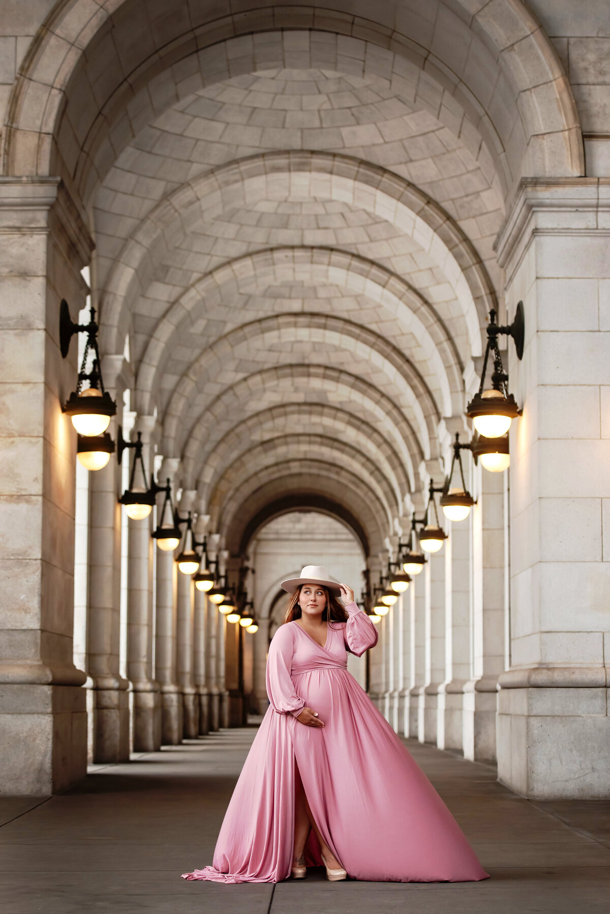 washington-dc-maternity-photographer-pregnant-mom-in-pink-gown-and-hat-in-entry-to-union-station
