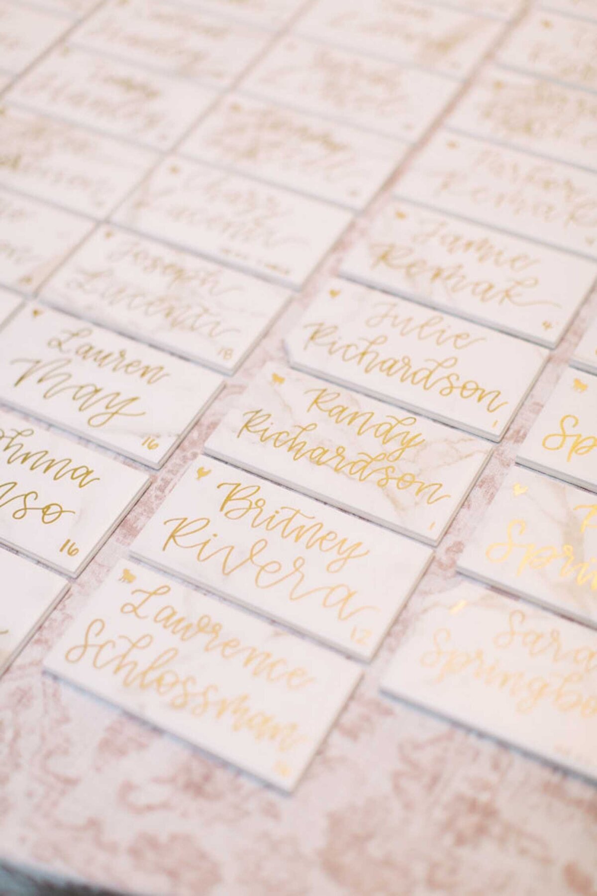 Tile and calligraphy place cards on a floral printed linen at a luxury Chicago outdoor garden wedding.