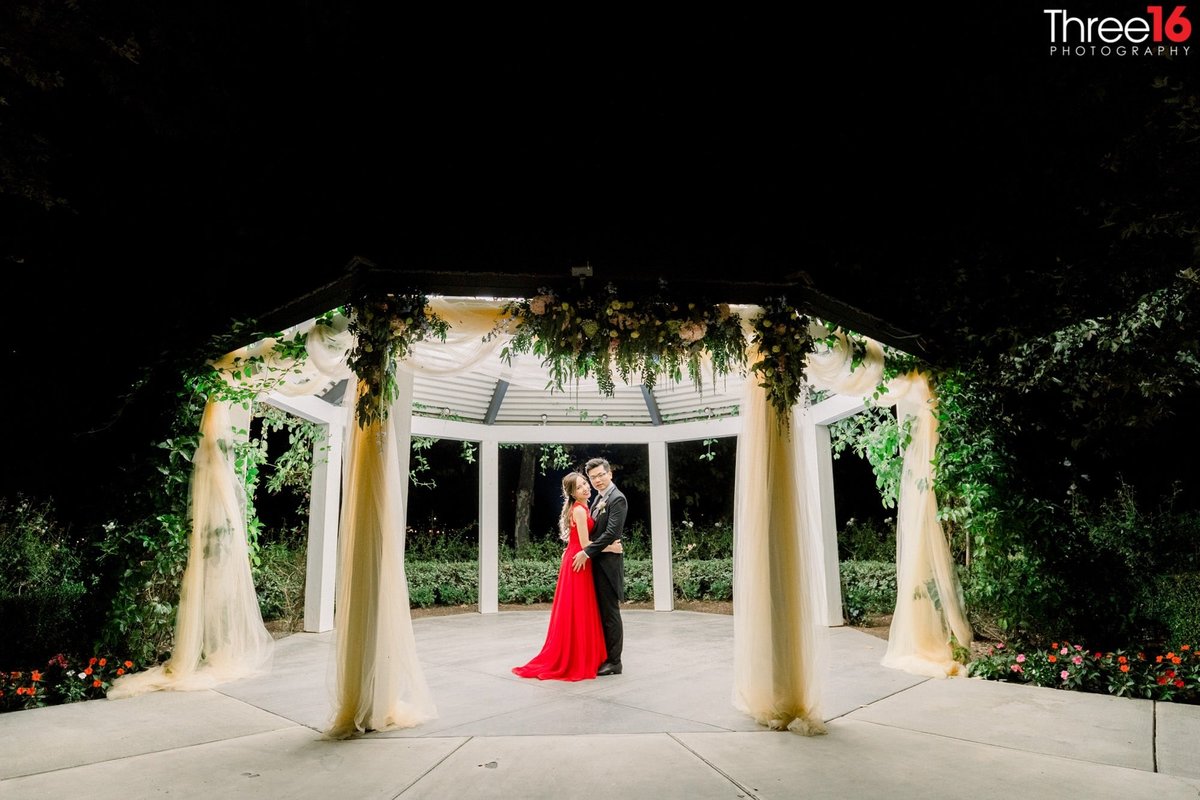 Night shot of the Bride and Groom posing together under a lit up gazebo