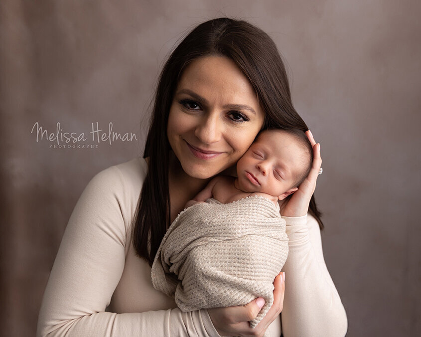 Mom holds newborn son in arms for newborn session located in Greensburg photo studio