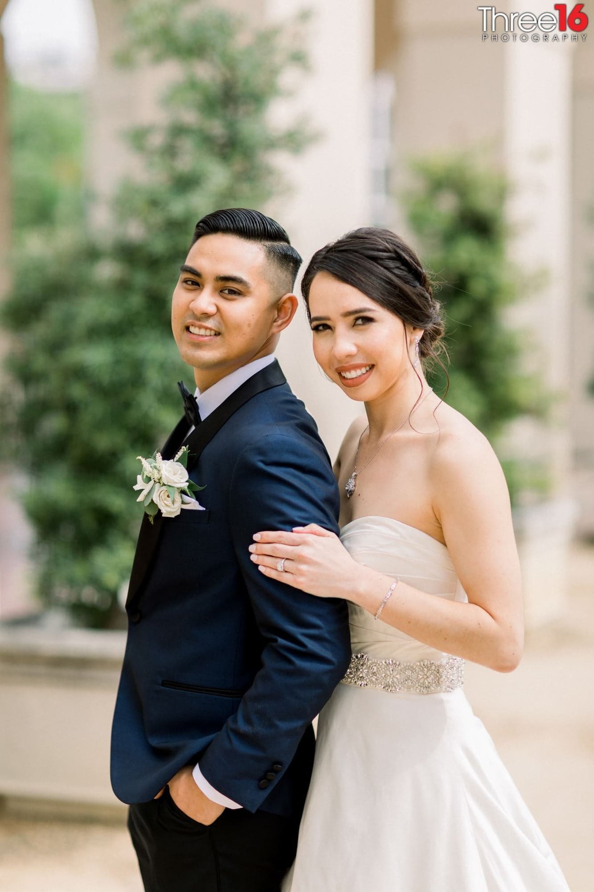 The Bride in her white dress and Groom  in his tuxedo posing for the photographer