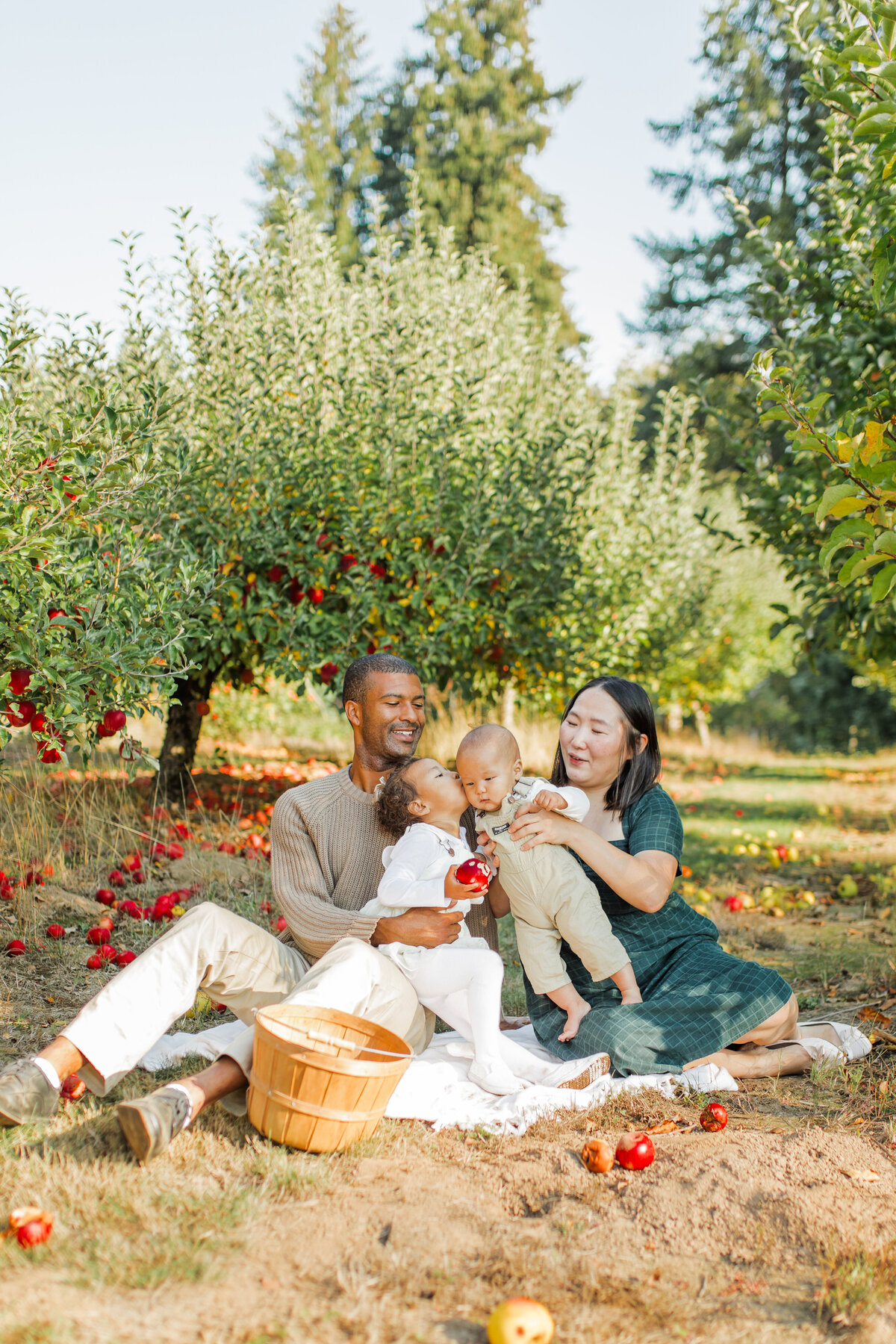 Family sitting in an orchard, parents holding babies