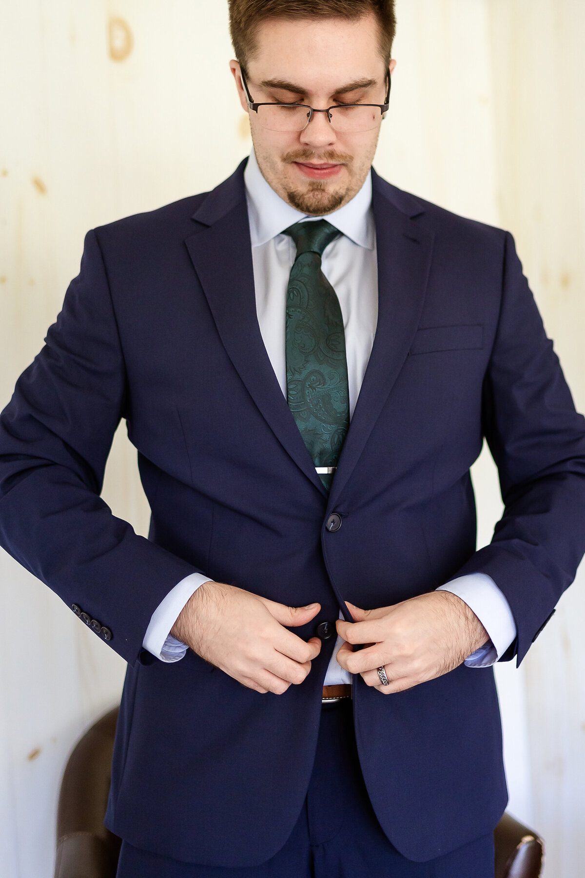 Groom in navy blue suit buttoning his jacket at NH wedding venue Allrose Farm
