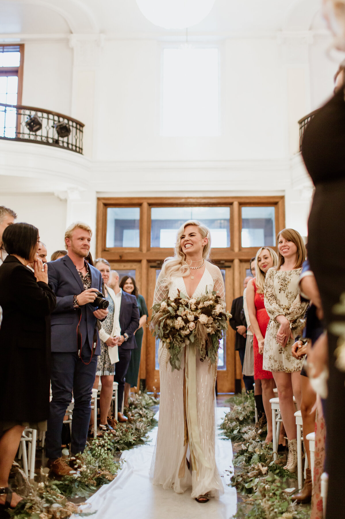 A beautiful beaming bride walking down the aisle captured by Fort Worth wedding photographer, Megan Christine Studio