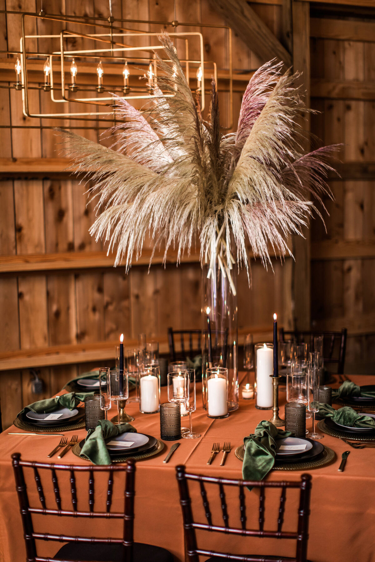 Large pampas arrangement surrounded by candles on cooper colored table cloth