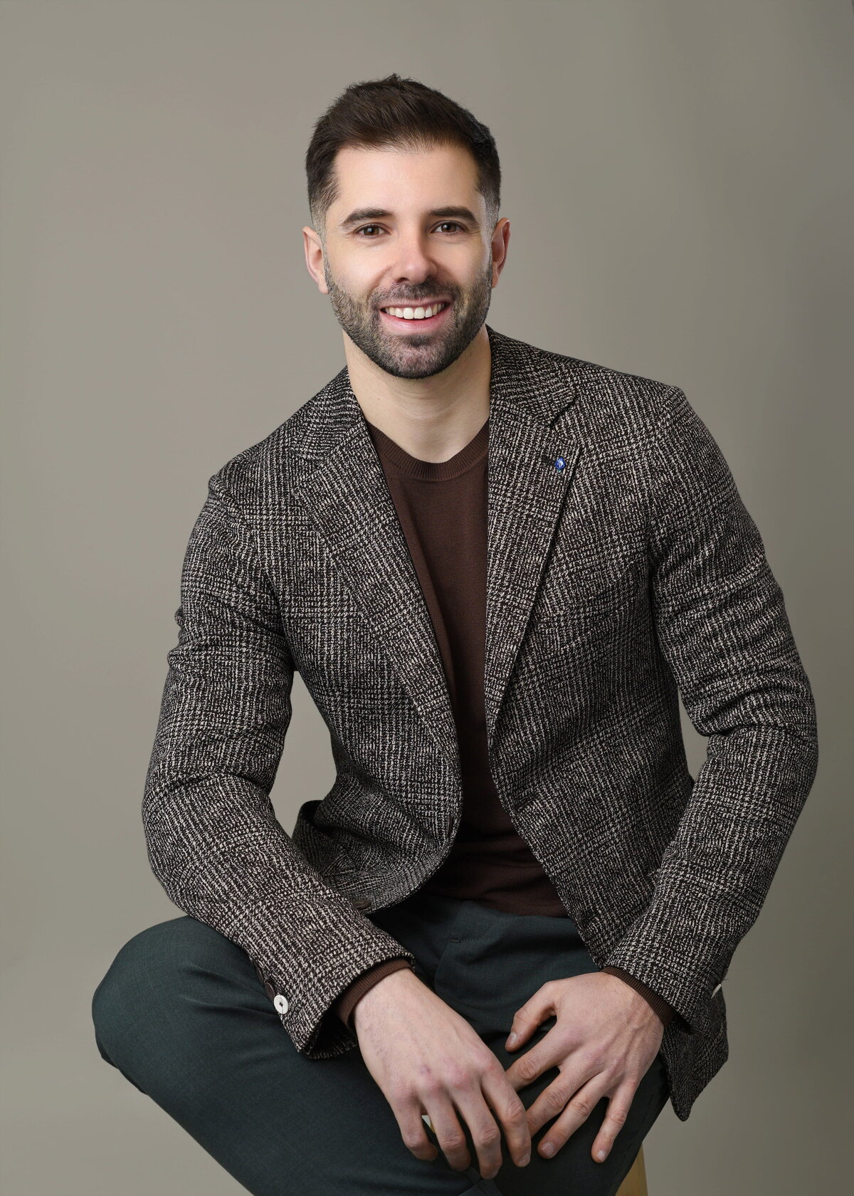 Young creative professional in casual attire smiling confidently in a studio headshot by a Toronto headshot photographer.