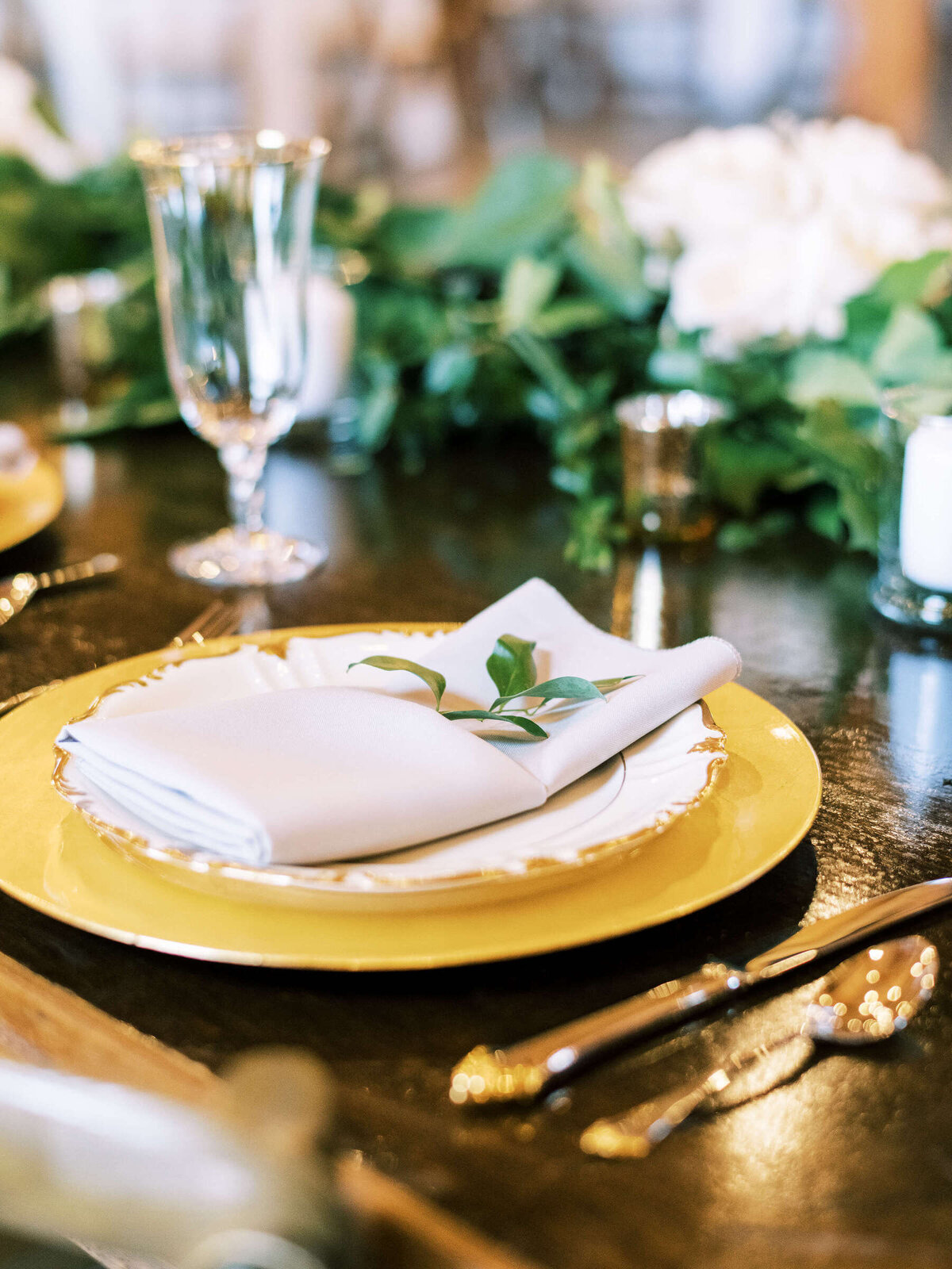 Elegant wedding place setting with gold plates and greenery