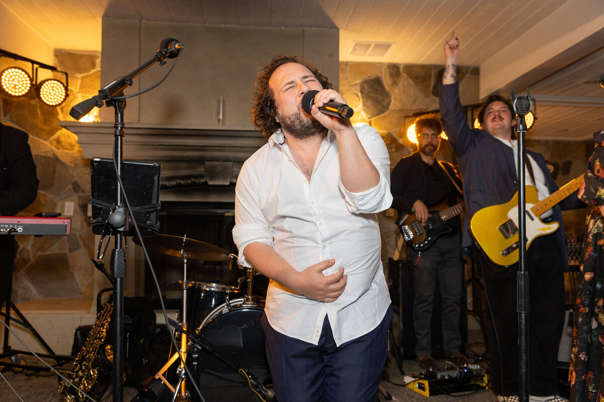 A groom singing on stage with a band