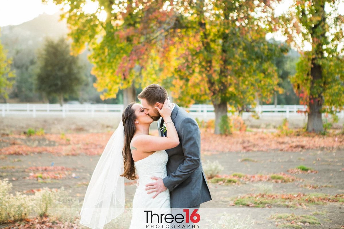 Bride and Groom share a big kiss in a field at the Boulder Oaks Golf Club