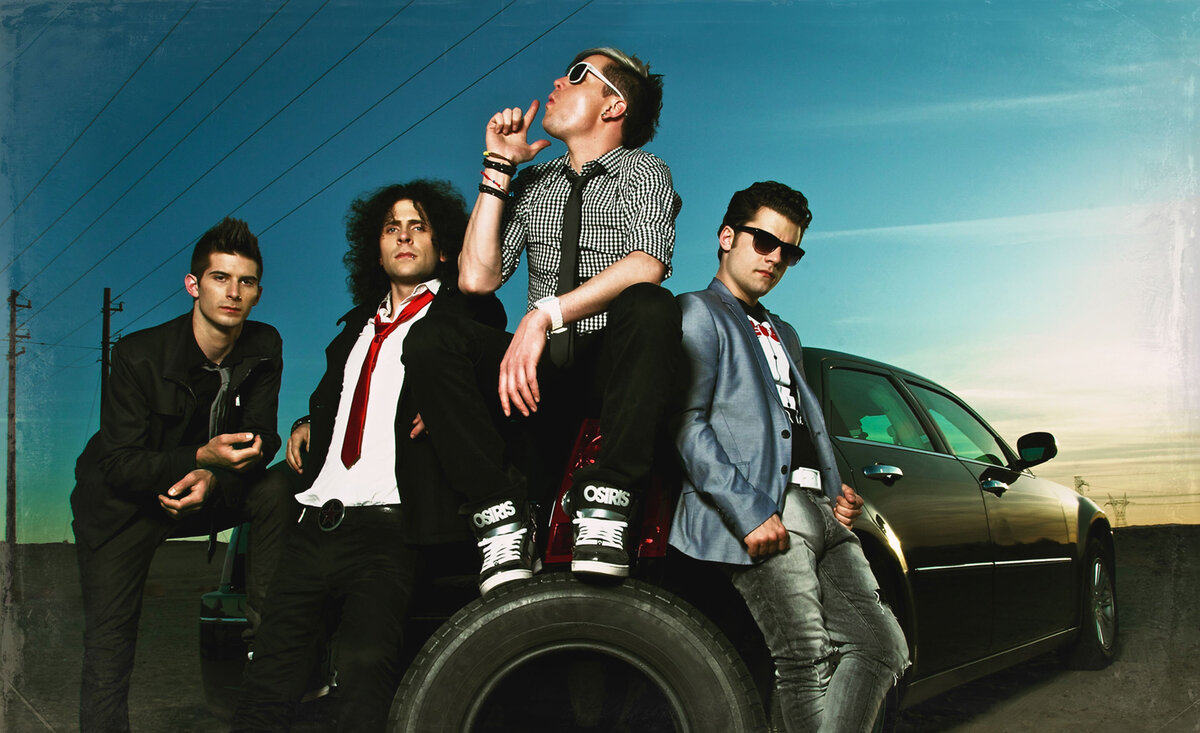 Musical band photo Faber Drive sitting against black car trunk with spare tire sun setting behind