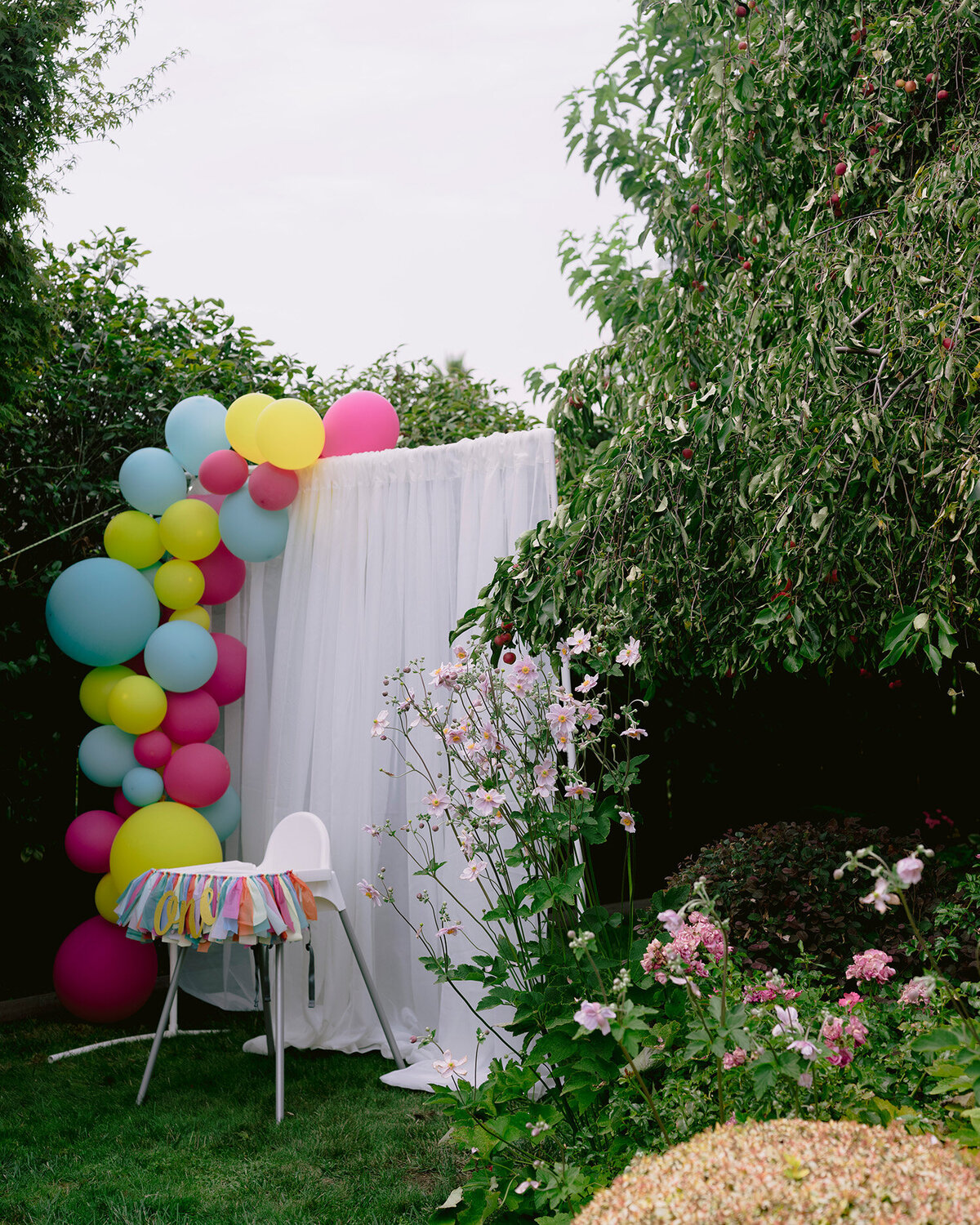 Backyard birthday party setup with a decorated high chair, colorful balloons, and fiesta-themed decor in Novato, photographed by a San Francisco Bay Area first birthday party photographer.