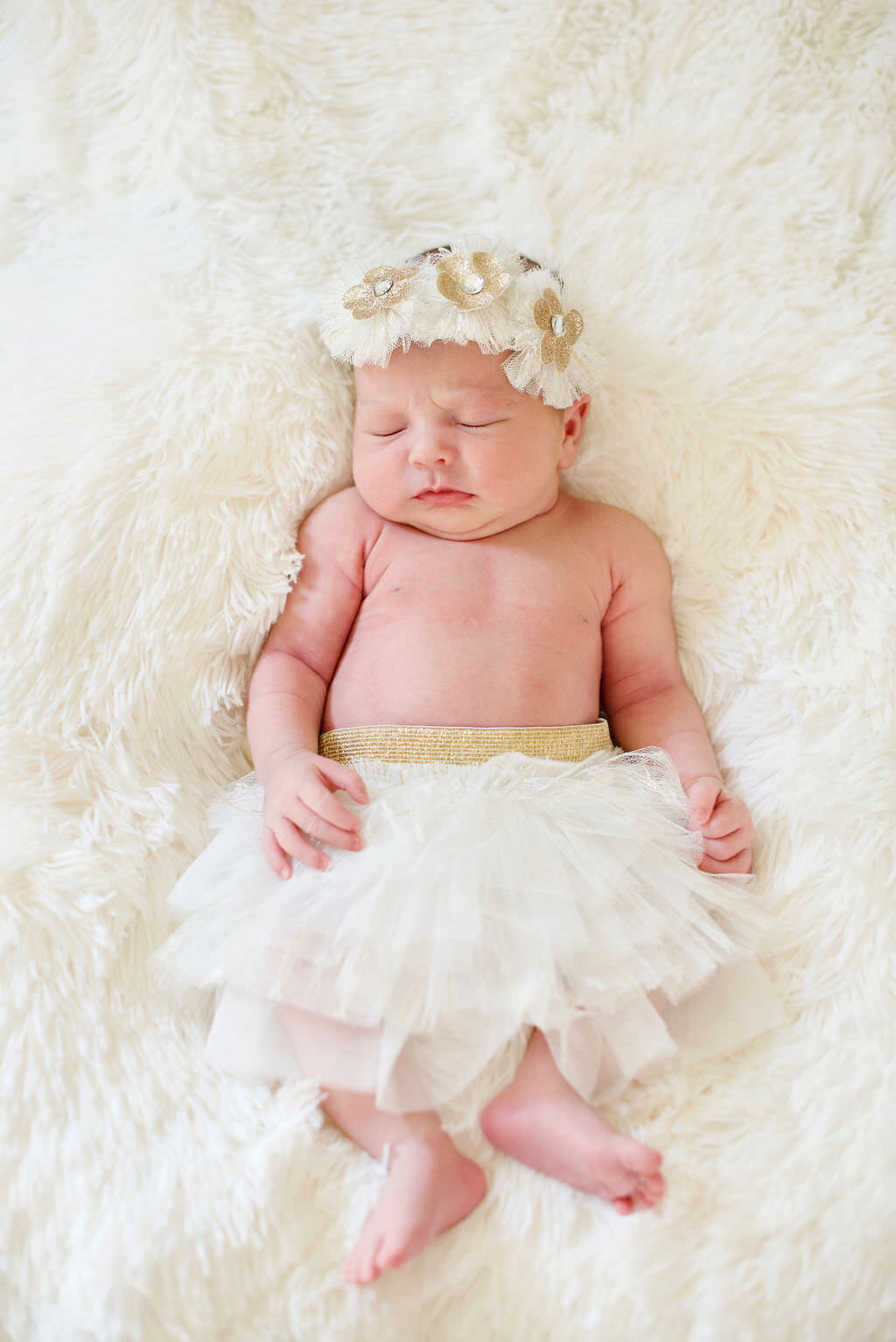A newborn baby in a white tutu.