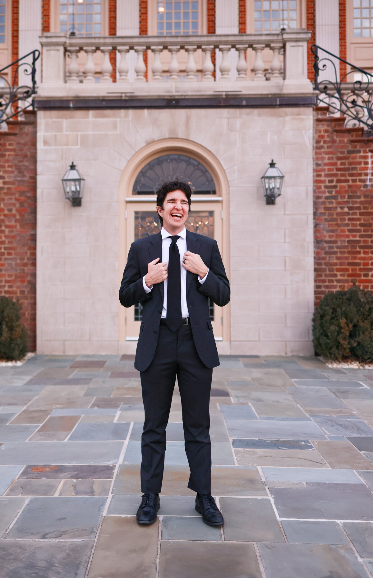 groom smiling and holding jacket at Rust Manor in Richmond Virginia by destination wedding photographer Amanda Richardson Photography