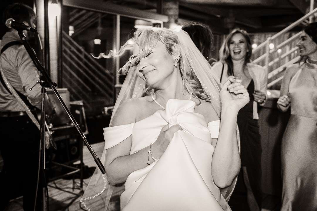 Bride joyfully dancing during wedding reception, captured in black and white at a lively New Jersey celebration.